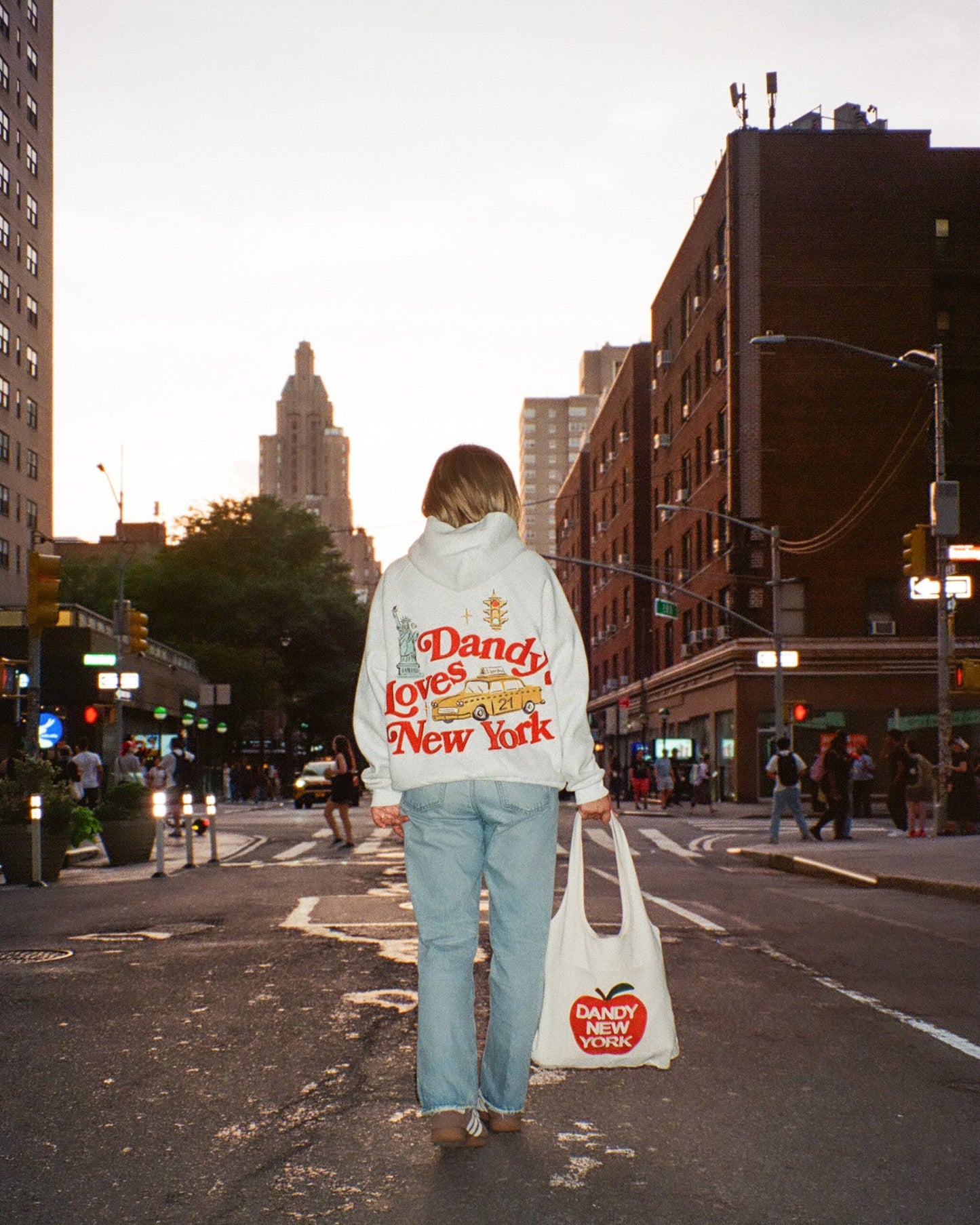 Person walking down a city street holding a 'Dandy New York' bag