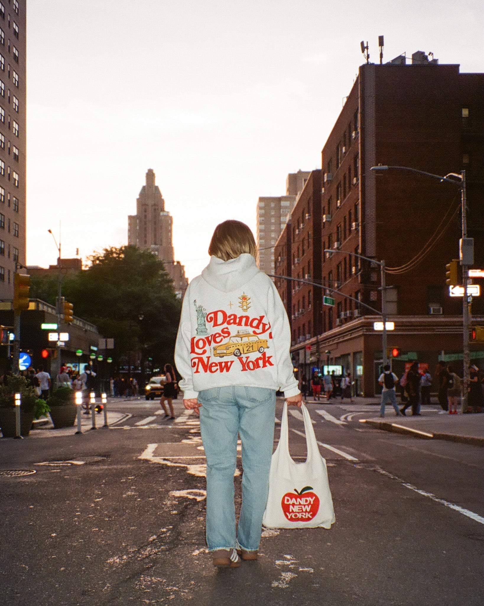 Person walking down a city street holding a 'Dandy New York' bag