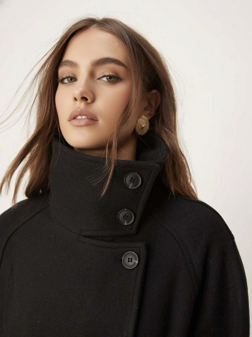 Black high-neck jacket with asymmetrical buttons and structured silhouette, featuring wide sleeves and a minimalist design for modern everyday styling.